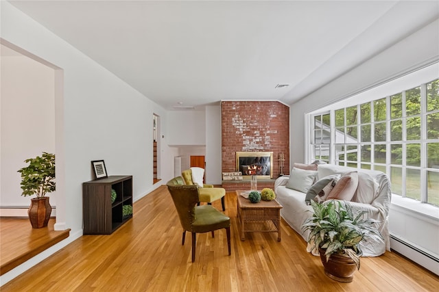 living room with baseboard heating, light wood finished floors, and plenty of natural light