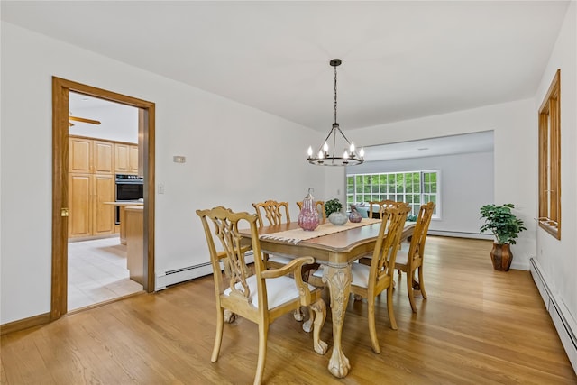 dining room with a baseboard heating unit, baseboard heating, light wood-type flooring, a chandelier, and baseboards