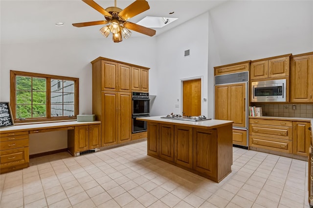 kitchen featuring built in appliances, light countertops, decorative backsplash, a skylight, and ceiling fan