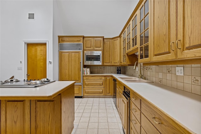 kitchen featuring built in appliances, a sink, decorative backsplash, light tile patterned flooring, and light countertops