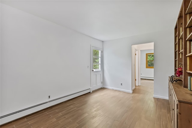 empty room featuring a baseboard radiator, light wood-style flooring, and baseboards