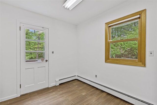 doorway with light wood-type flooring, a baseboard heating unit, and baseboards
