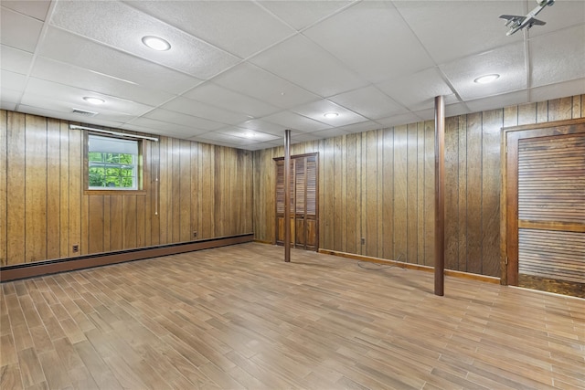 below grade area featuring baseboard heating, wood finished floors, wood walls, and a paneled ceiling