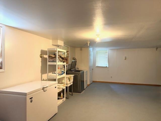 below grade area with separate washer and dryer, white fridge, and baseboards