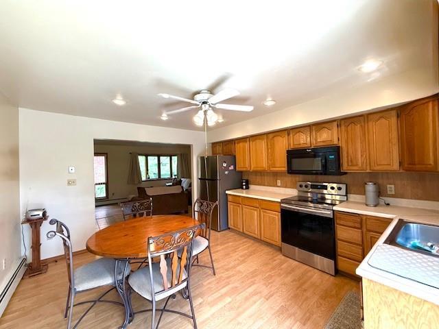 kitchen featuring appliances with stainless steel finishes, a baseboard heating unit, light countertops, light wood-type flooring, and brown cabinets