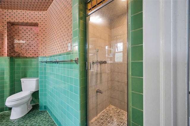 full bath featuring a shower stall, toilet, tile walls, and wainscoting