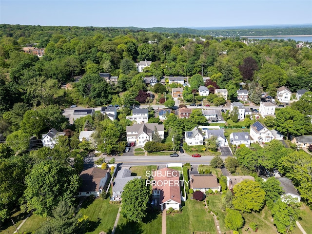 aerial view of property's location featuring a forest and nearby suburban area