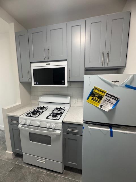 2925 Matthews Ave Unit 2H, Bronx, NY 10467 - kitchen featuring freestanding refrigerator, built in microwave, white gas range oven, gray cabinets, and light countertops