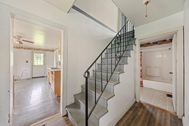 staircase with ceiling fan, baseboards, and wood finished floors