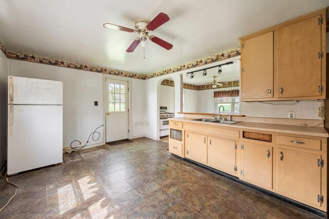 kitchen with white appliances, a sink, a ceiling fan, arched walkways, and light countertops