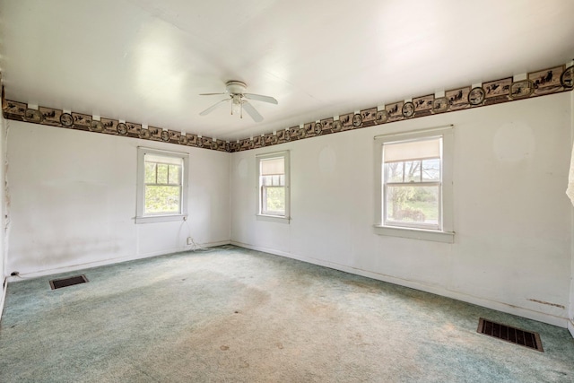 spare room with a ceiling fan, light colored carpet, and baseboards
