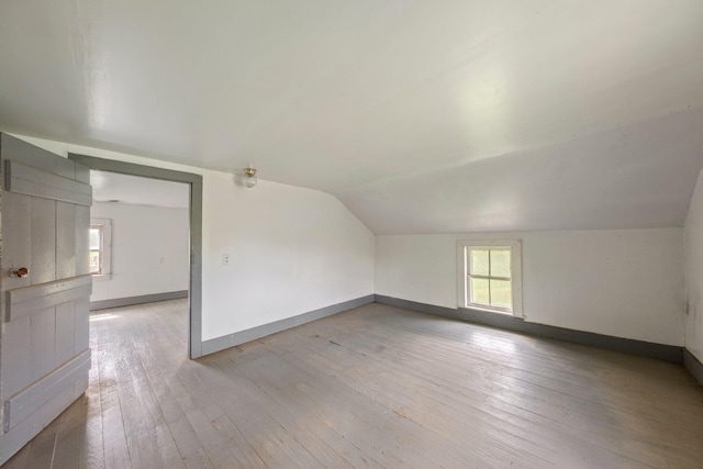 bonus room featuring light wood finished floors, lofted ceiling, and baseboards