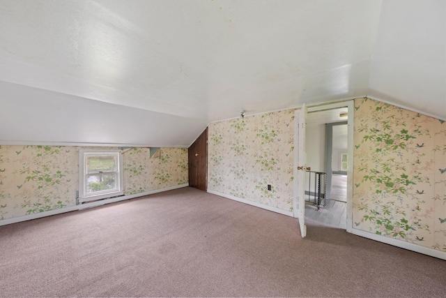 additional living space with wallpapered walls, lofted ceiling, carpet, and baseboards