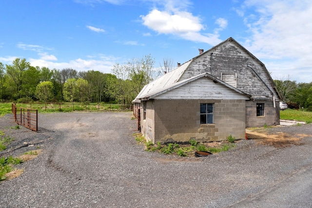 view of side of property with fence, a barn, driveway, and a gambrel roof