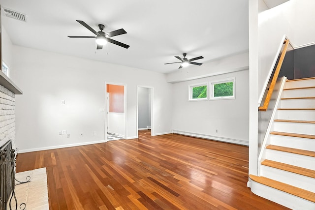 1755 Parmly Rd, Mohegan Lake, NY 10547 - unfurnished living room featuring baseboard heating, a ceiling fan, wood finished floors, stairs, and a brick fireplace