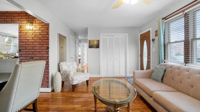 living area with wood finished floors, a ceiling fan, and baseboards