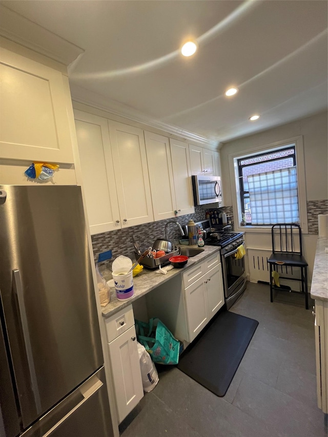 kitchen featuring appliances with stainless steel finishes, a sink, decorative backsplash, white cabinets, and recessed lighting