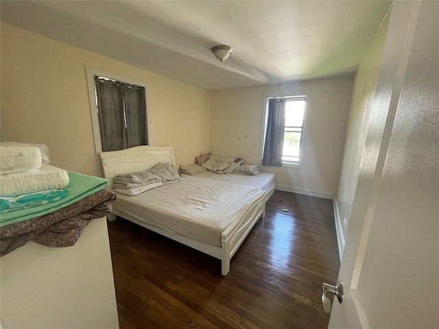 bedroom with dark wood-type flooring and baseboards