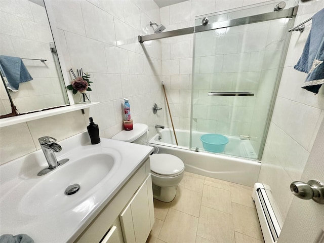 bathroom featuring baseboard heating, tile walls, toilet, vanity, and enclosed tub / shower combo