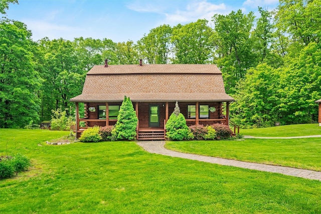 view of front of home featuring log exterior, covered porch, a front yard, and roof with shingles