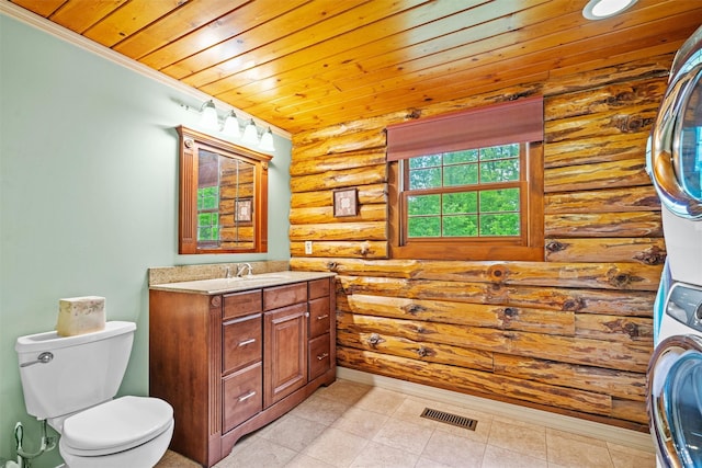 bathroom with rustic walls, estacked washer and dryer, wood ceiling, toilet, and vanity