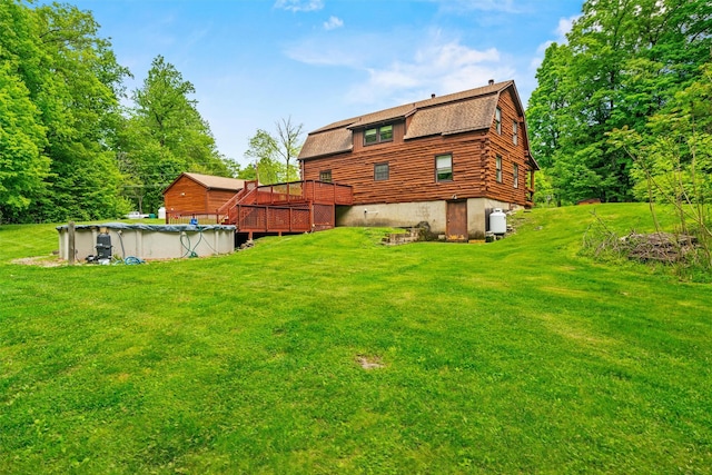 view of grassy yard featuring a wooden deck and a covered pool