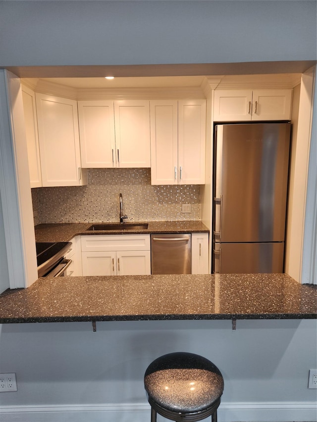 1 Bengeyfield Dr Unit 2G, East Williston, NY 11596 - kitchen featuring appliances with stainless steel finishes, a sink, white cabinetry, dark stone counters, and decorative backsplash