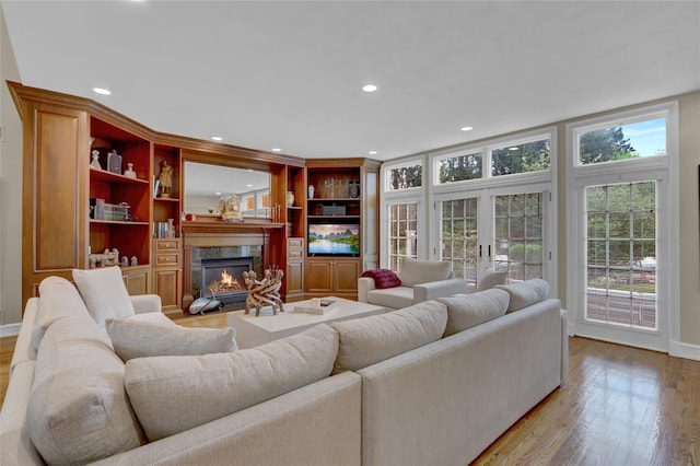 living area featuring a high end fireplace, wood finished floors, recessed lighting, and baseboards