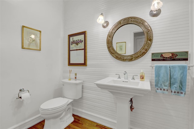 bathroom featuring toilet, wood finished floors, and baseboards