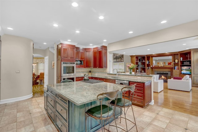 kitchen featuring stainless steel appliances, a kitchen island, a peninsula, a sink, and recessed lighting