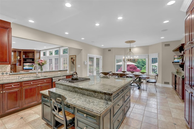 kitchen with a sink, stainless steel gas stovetop, a kitchen island, healthy amount of natural light, and recessed lighting