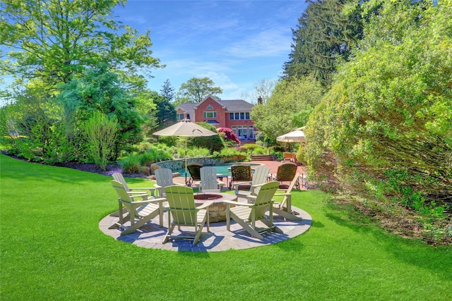 view of green lawn with a fire pit and a patio