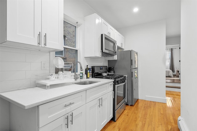 41AKA43 Sherwood Ave, Yonkers, NY 10704 - kitchen featuring appliances with stainless steel finishes, a sink, baseboard heating, backsplash, and white cabinets