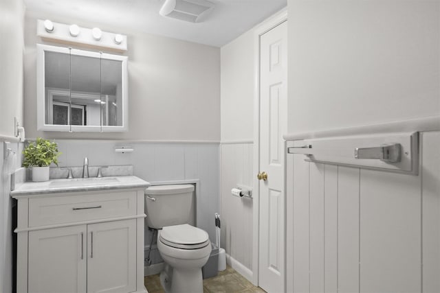 bathroom with toilet, a wainscoted wall, and vanity