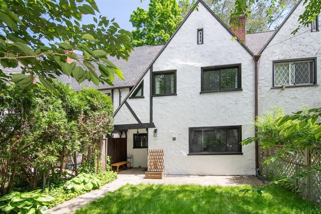 back of property with stucco siding, a chimney, and roof with shingles