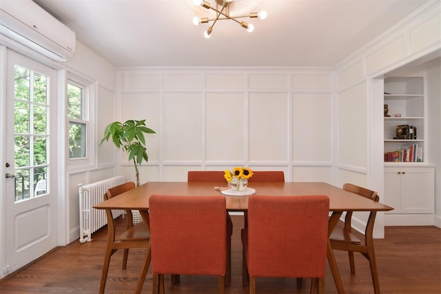 dining area featuring radiator, a decorative wall, an AC wall unit, built in shelves, and a chandelier