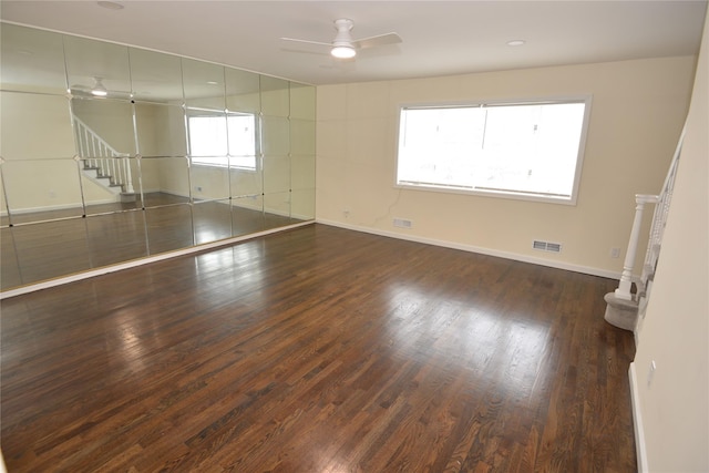 empty room with wood finished floors, baseboards, stairway, and a ceiling fan