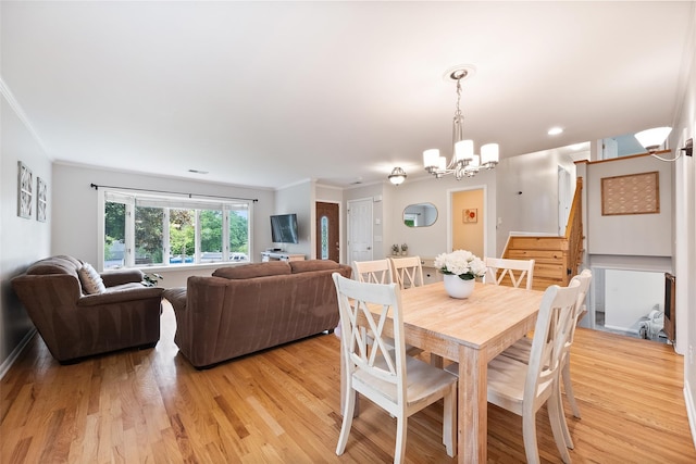 dining area with a chandelier, crown molding, light wood-type flooring, and stairs