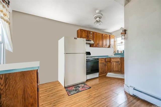80 Monell Ave, Islip, NY 11751 - kitchen with gas stove, freestanding refrigerator, under cabinet range hood, a baseboard radiator, and brown cabinets