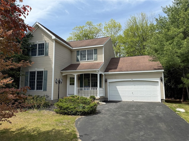traditional-style house featuring asphalt driveway, covered porch, an attached garage, a front lawn, and a shingled roof