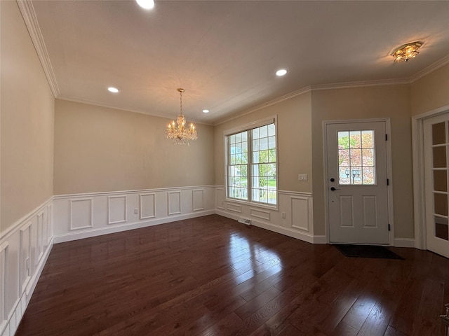 unfurnished dining area with a chandelier, dark wood finished floors, wainscoting, recessed lighting, and ornamental molding