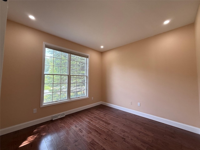 empty room featuring dark wood-style flooring, baseboards, and recessed lighting