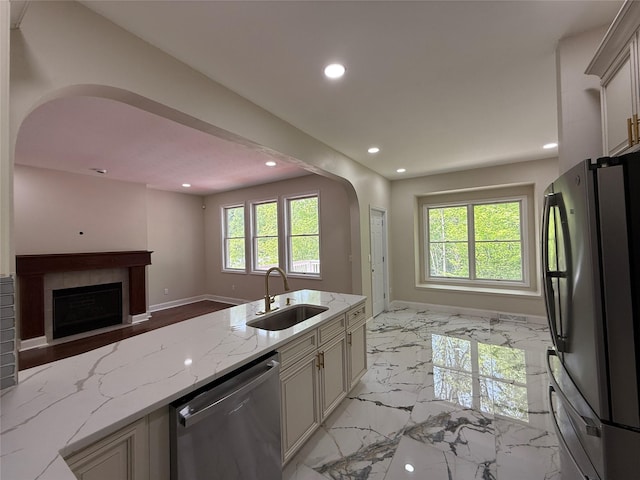 kitchen featuring dishwasher, a sink, freestanding refrigerator, open floor plan, and arched walkways