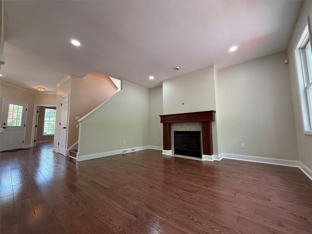 unfurnished living room featuring dark wood-style flooring, baseboards, stairs, a fireplace, and recessed lighting