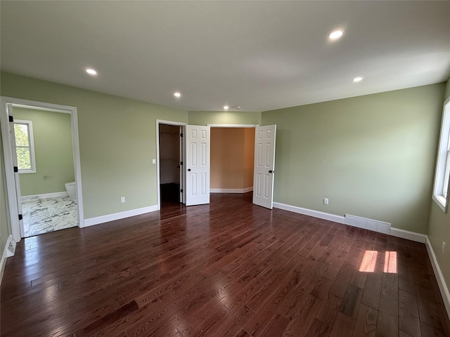 unfurnished bedroom with dark wood-type flooring, baseboards, recessed lighting, and connected bathroom