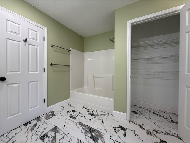 bathroom featuring baseboards, marble look tile flooring, and  shower combination