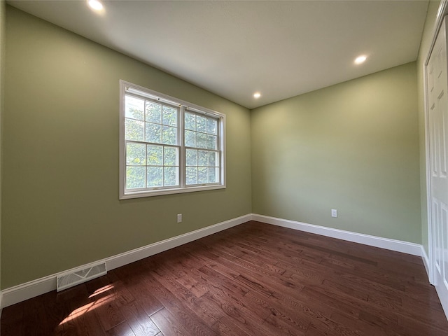 empty room with dark wood finished floors, baseboards, and recessed lighting