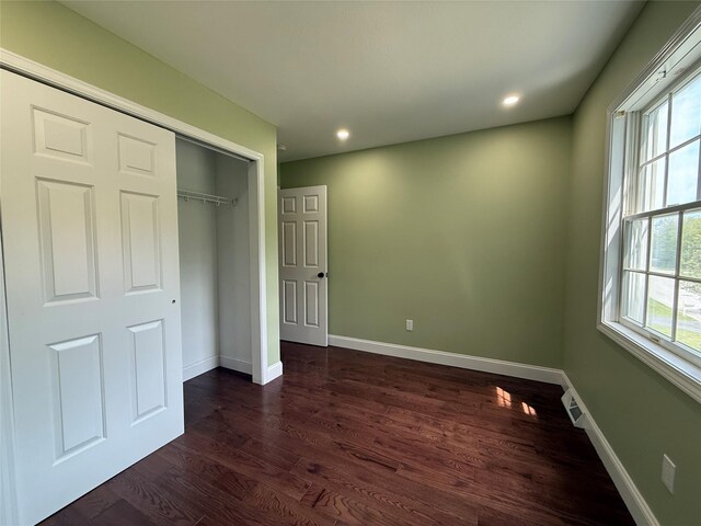 unfurnished bedroom featuring dark wood finished floors, baseboards, recessed lighting, and a closet