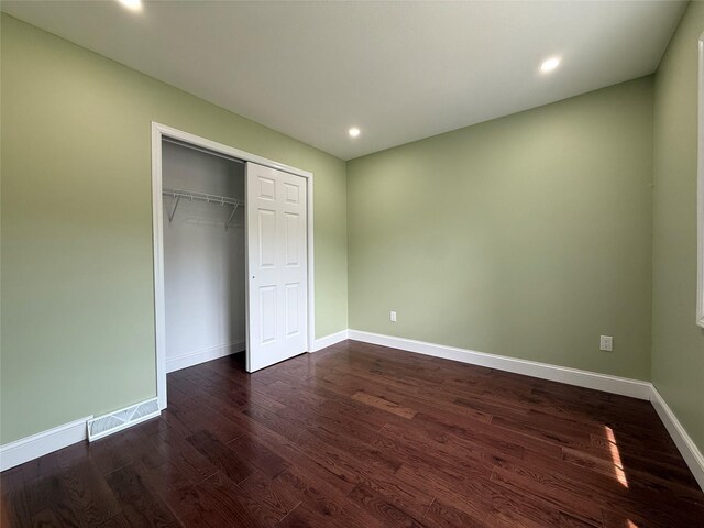 unfurnished bedroom featuring dark wood-type flooring, baseboards, recessed lighting, and a closet