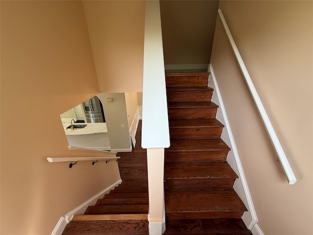 staircase featuring baseboards and wood finished floors